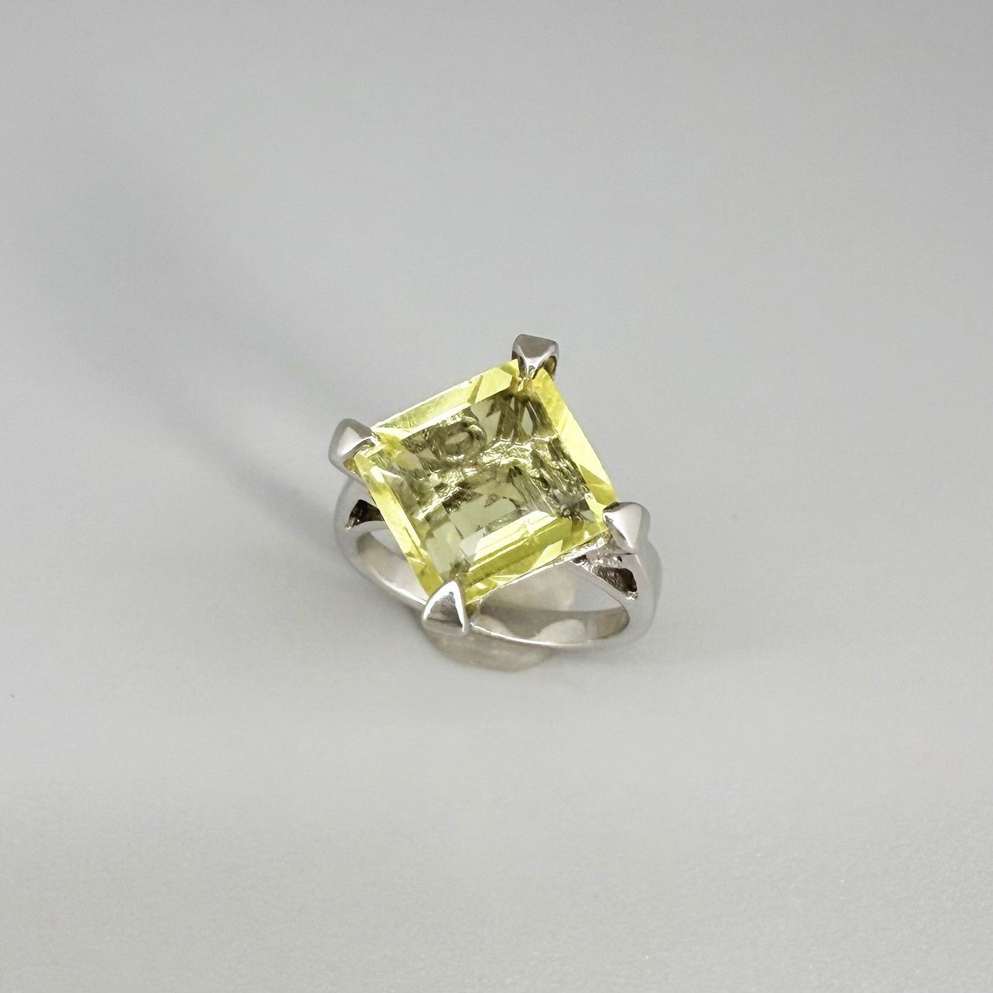 Lemon quartz solitaire ring in white gold plated sterling silver, featuring a rectangular faceted yellow gemstone, elegant and timeless design.