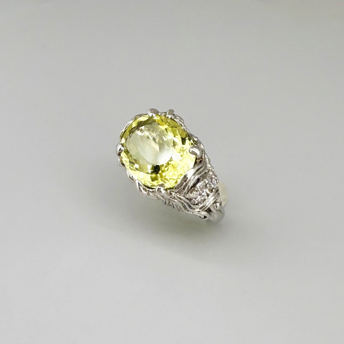 Lemon quartz ring in white gold plated sterling silver, featuring a faceted oval-cut yellow-green gemstone in an ornate vintage-inspired setting.