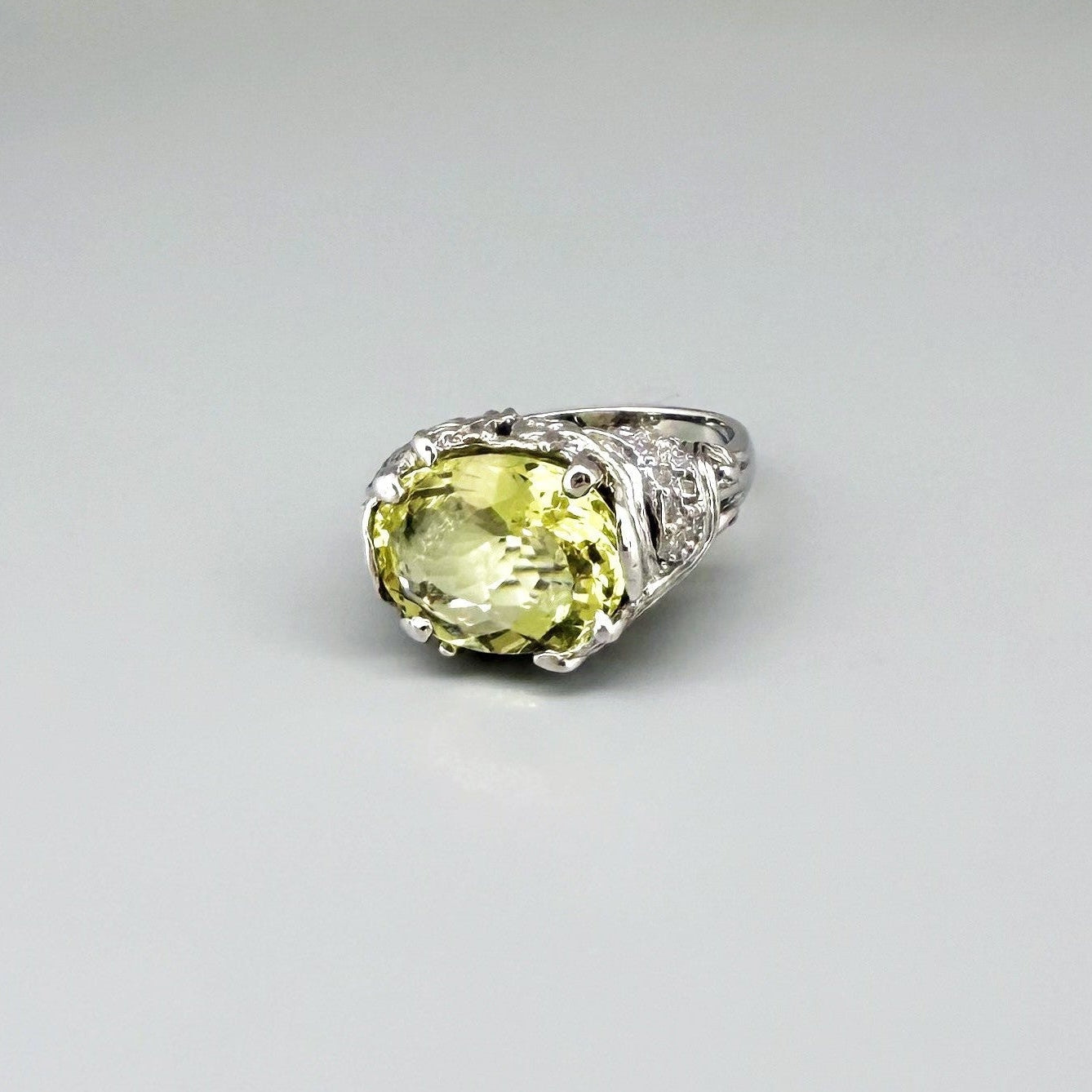 Lemon quartz ring in white gold plated sterling silver, featuring a faceted oval-cut yellow-green gemstone in an ornate vintage-inspired setting.
