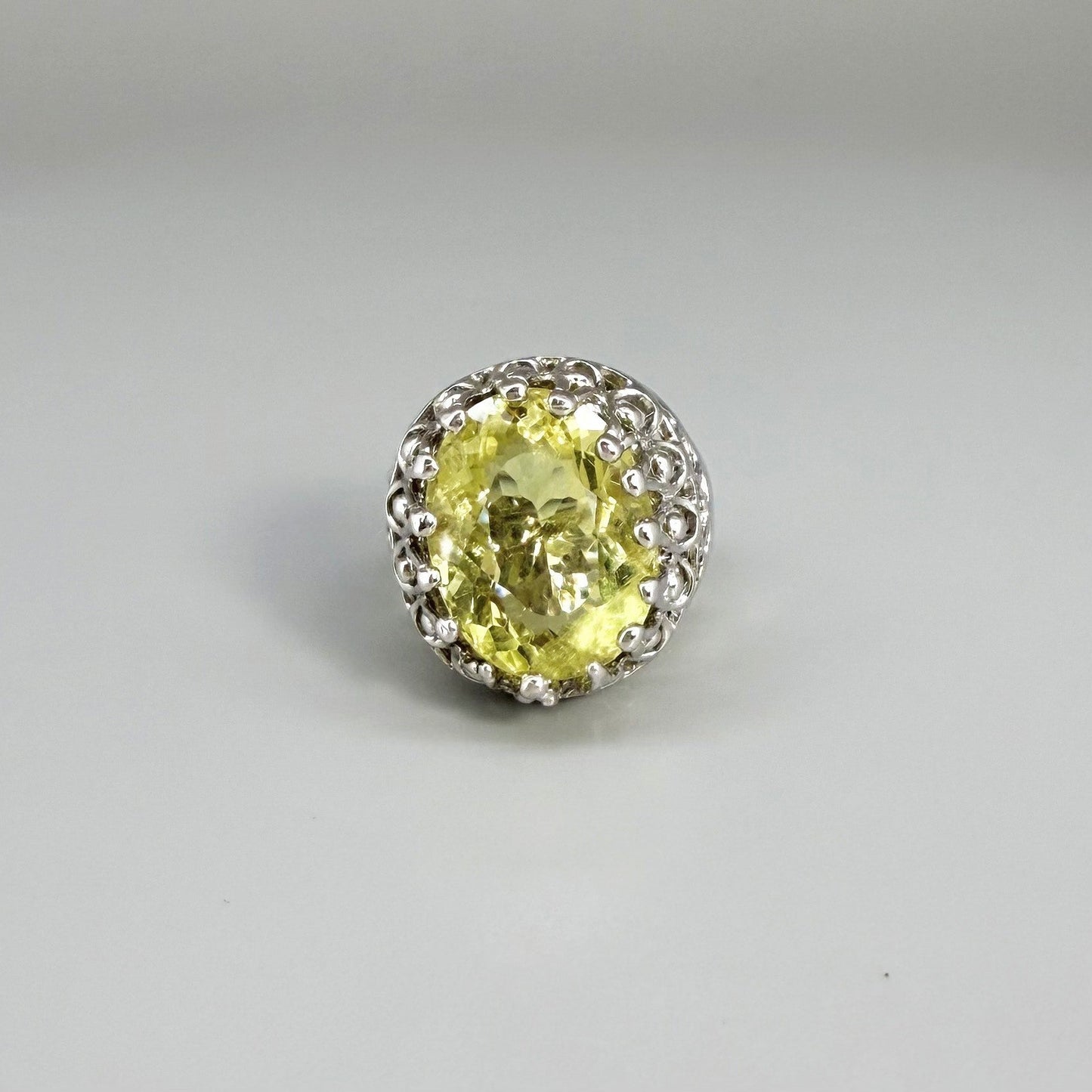 Statement ring with oval lemon quartz set in white gold plated sterling silver featuring intricate silver details and radiant yellow tones.