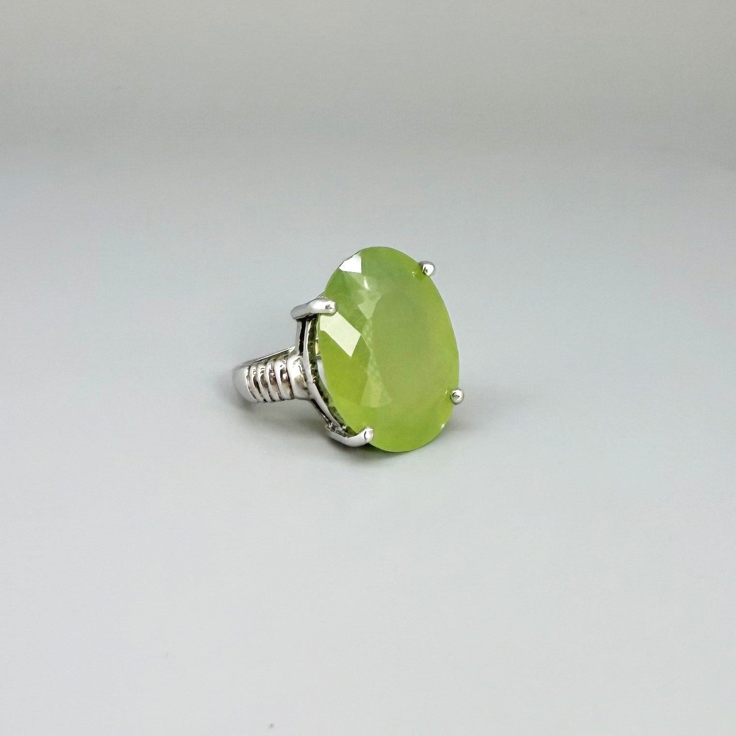 White gold plated sterling silver ring featuring an oval green quartz gemstone, elegant solitaire design with soft natural color.