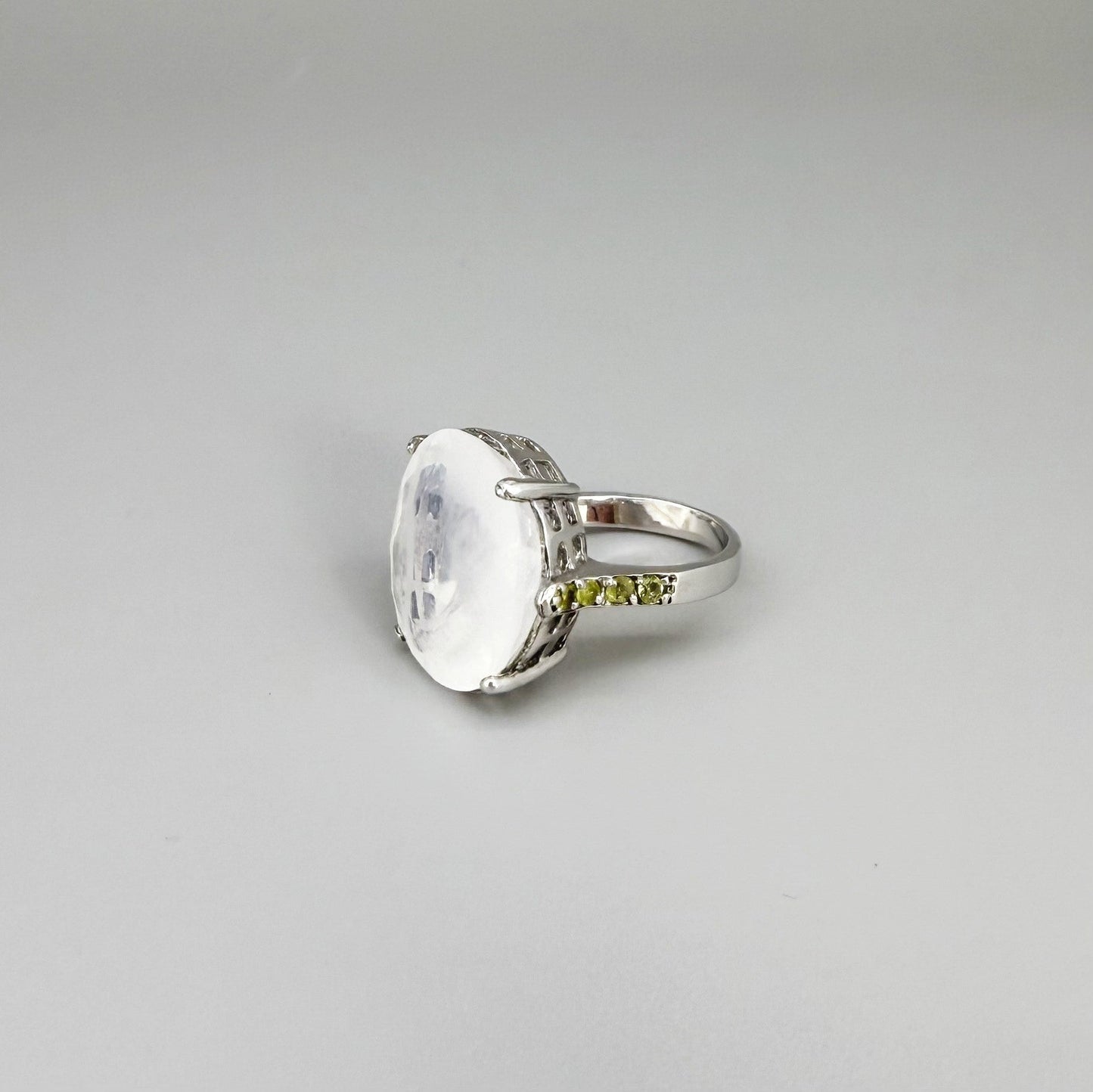 White quartz and sapphire ring in white gold plated sterling silver, featuring a faceted clear gemstone framed by blue sapphires, elegant and refined design.