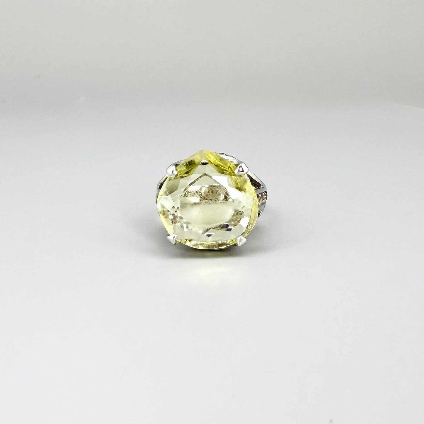 White gold plated sterling silver ring featuring a lemon quartz gemstone surrounded by orange sapphires in a halo design.