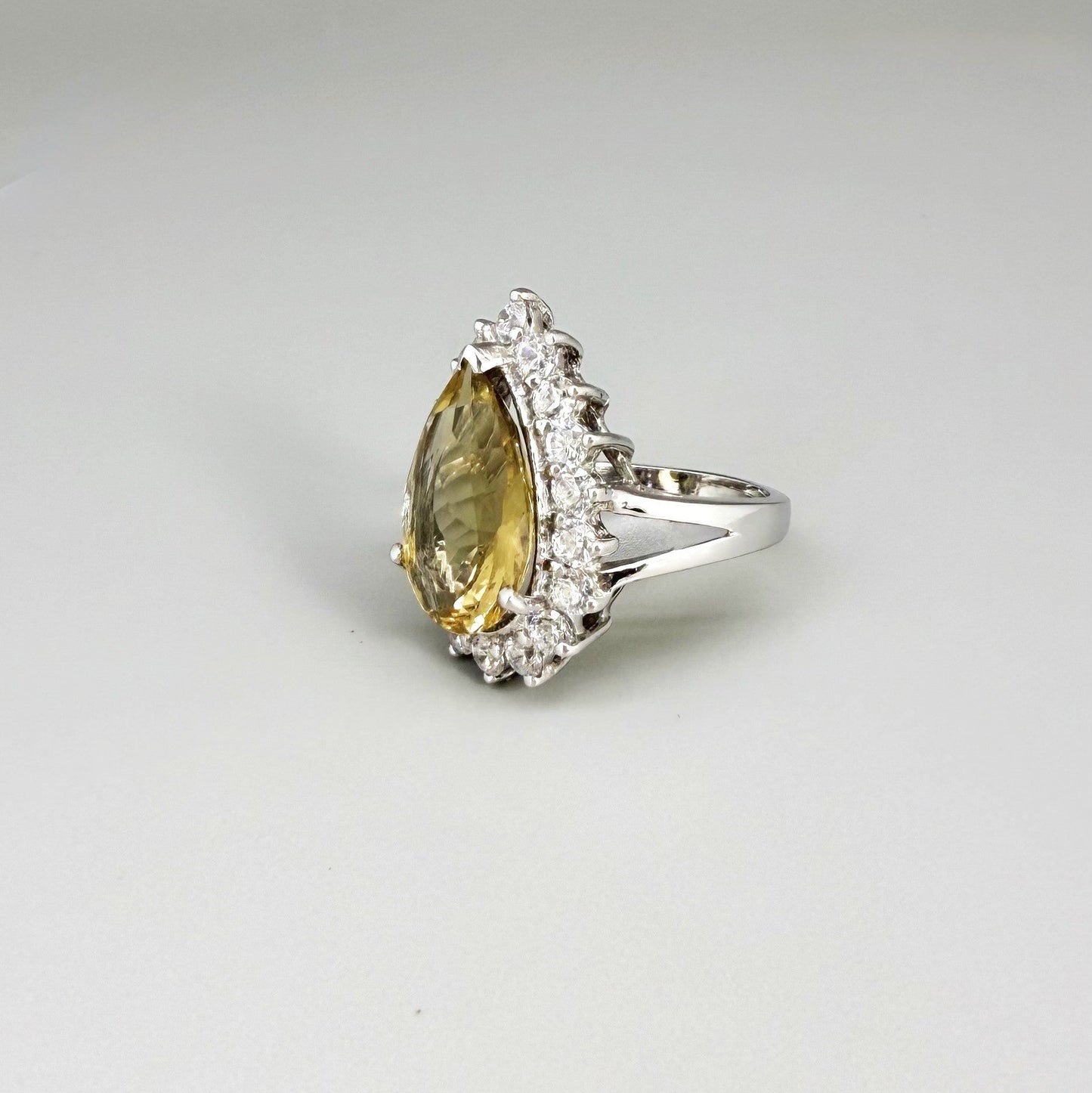 Citrine and CZ ring in white gold plated sterling silver, featuring a pear-shaped golden-yellow gemstone surrounded by clear cubic zirconia halo, elegant and refined design