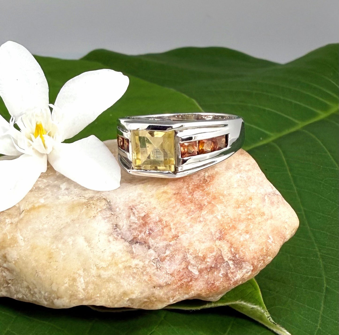 Citrine and sapphire ring in white gold plated sterling silver, featuring a rectangular golden-yellow gemstone flanked by orange sapphires, elegant and timeless design.