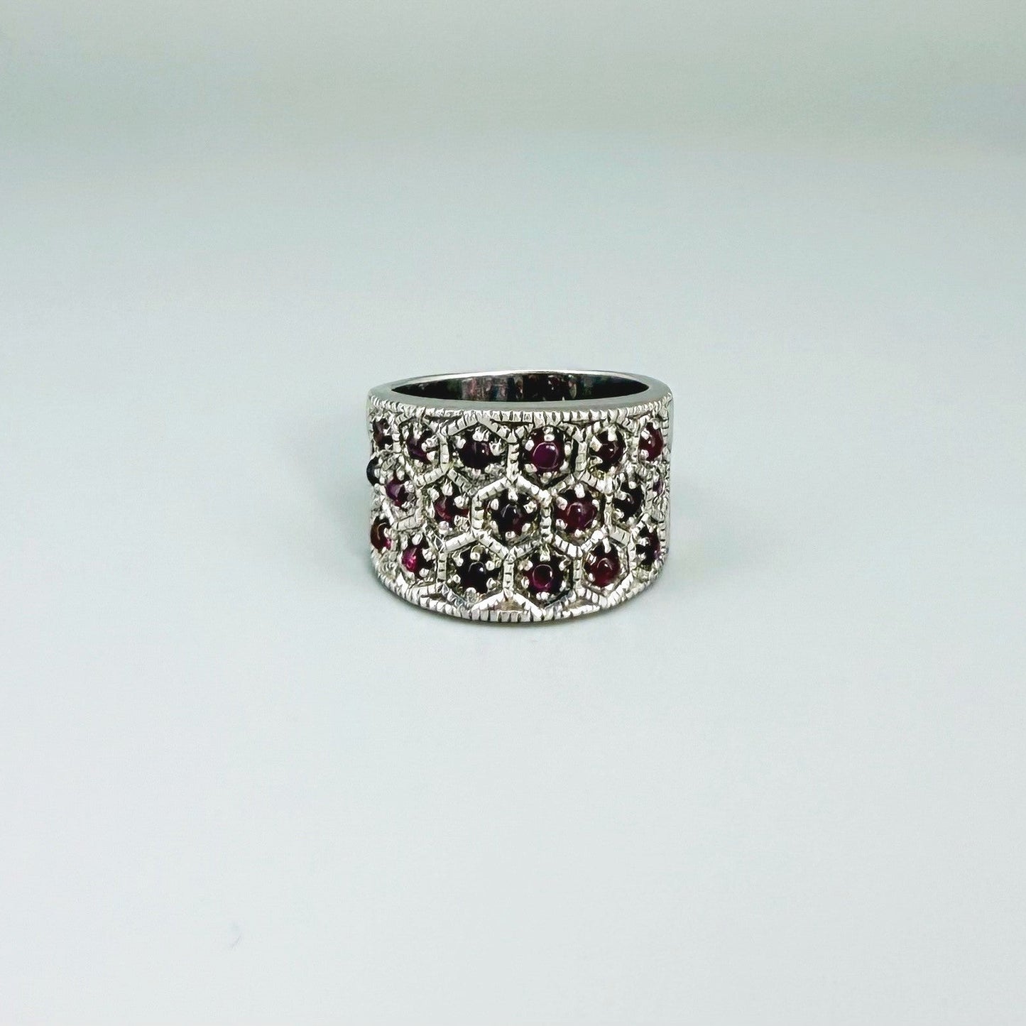 Rhodolite band ring in white gold plated sterling silver, featuring faceted rose-violet gemstones in a wide design, elegant and feminine style.