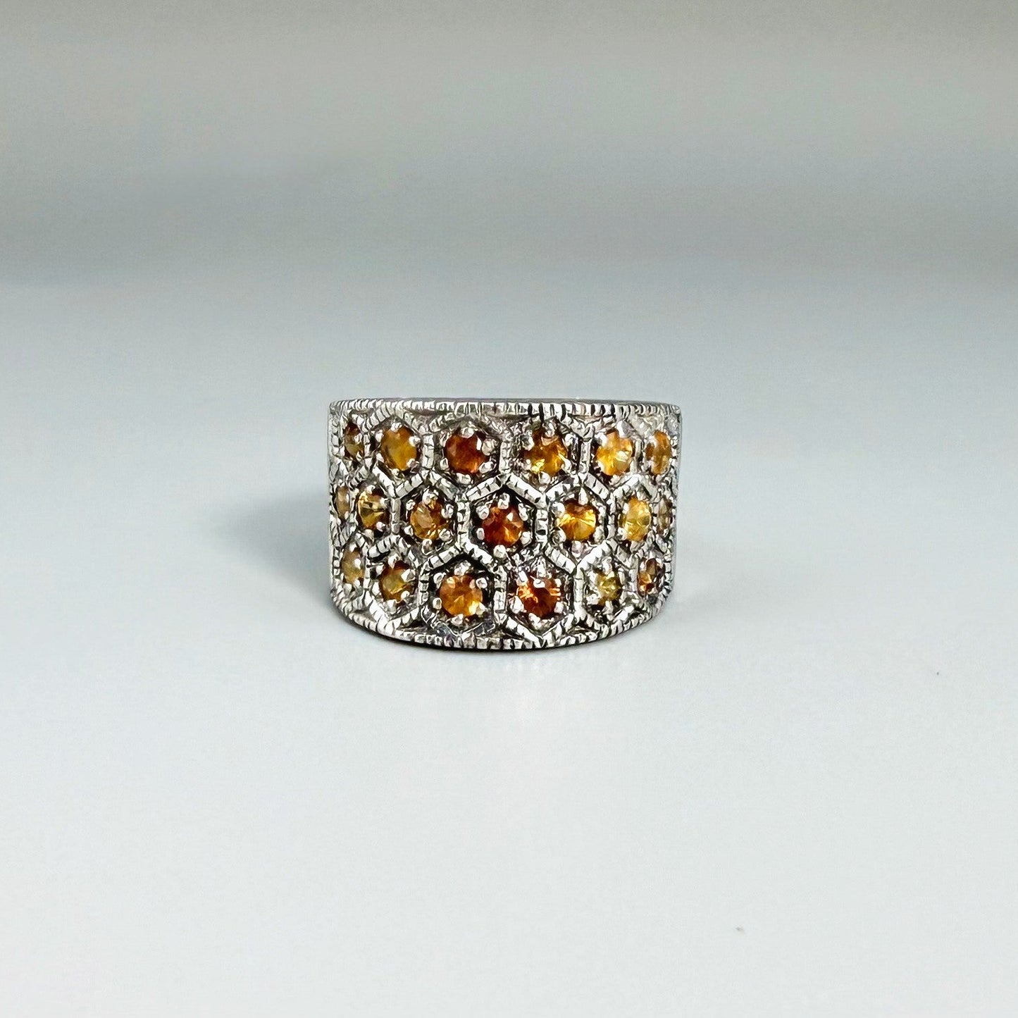 Wide band orange sapphire ring in white gold plated sterling silver featuring faceted sapphires in bright amber hues for a warm, elegant shine.