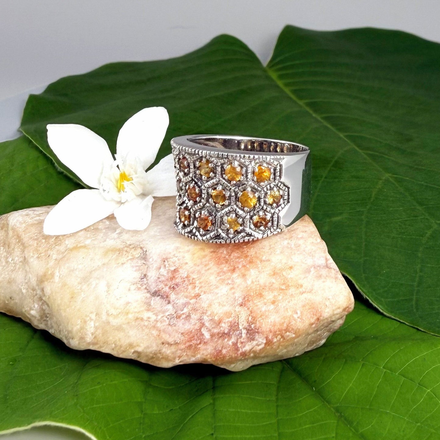 Wide band orange sapphire ring in white gold plated sterling silver featuring faceted sapphires in bright amber hues for a warm, elegant shine.