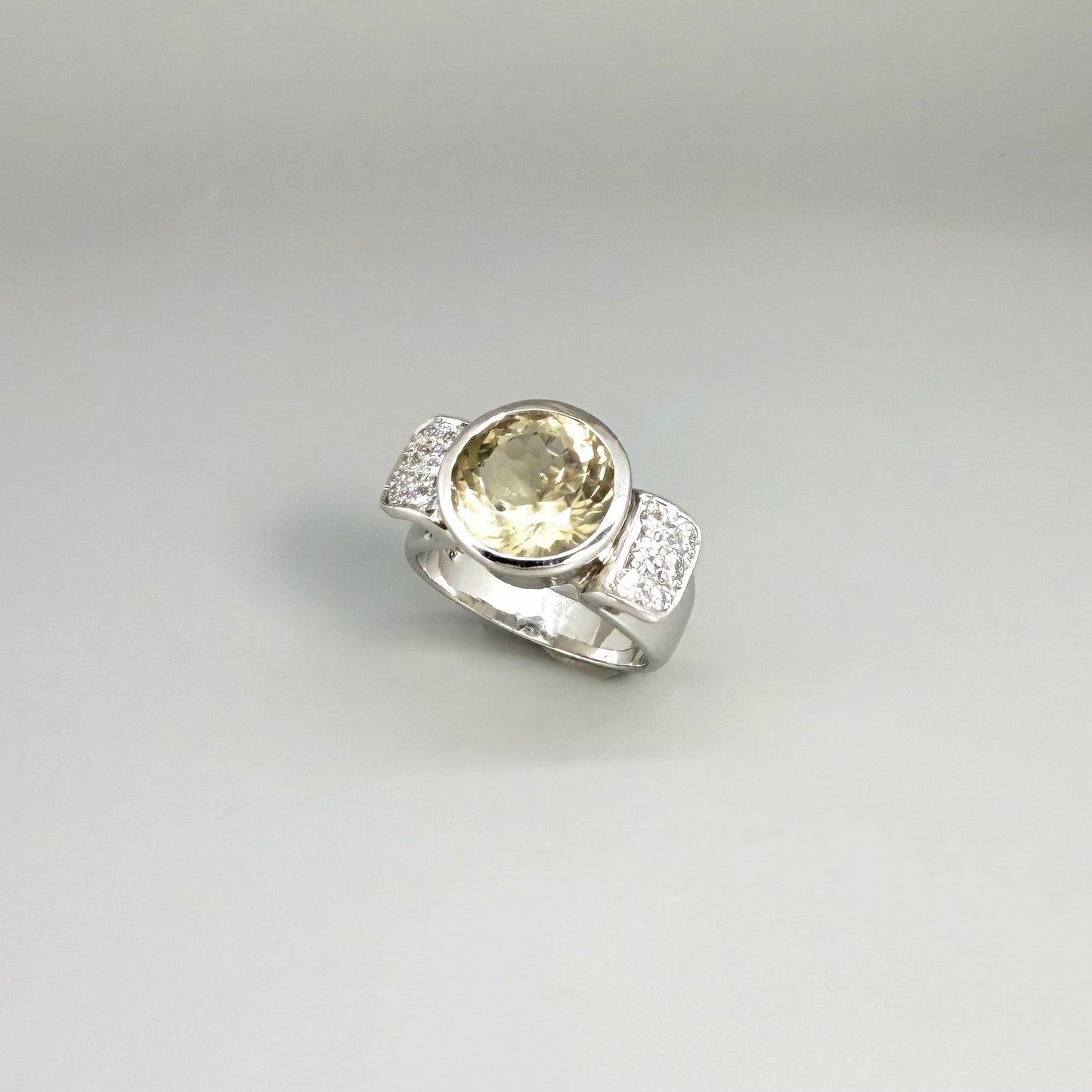 Citrine and CZ ring in white gold plated sterling silver, featuring a faceted golden gemstone with sparkling accents along the band, elegant and radiant design.