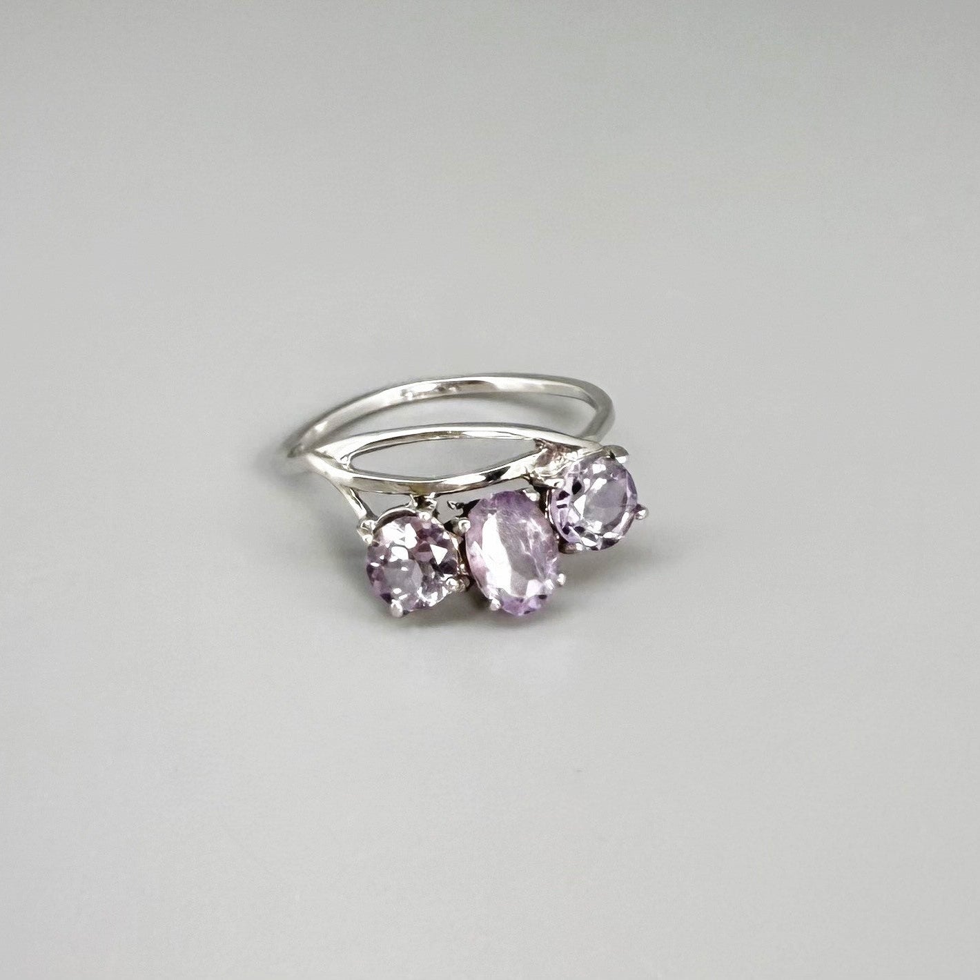 Three-stone amethyst ring in white gold plated sterling silver, featuring natural violet gemstones with soft lavender brilliance, elegant and feminine design.