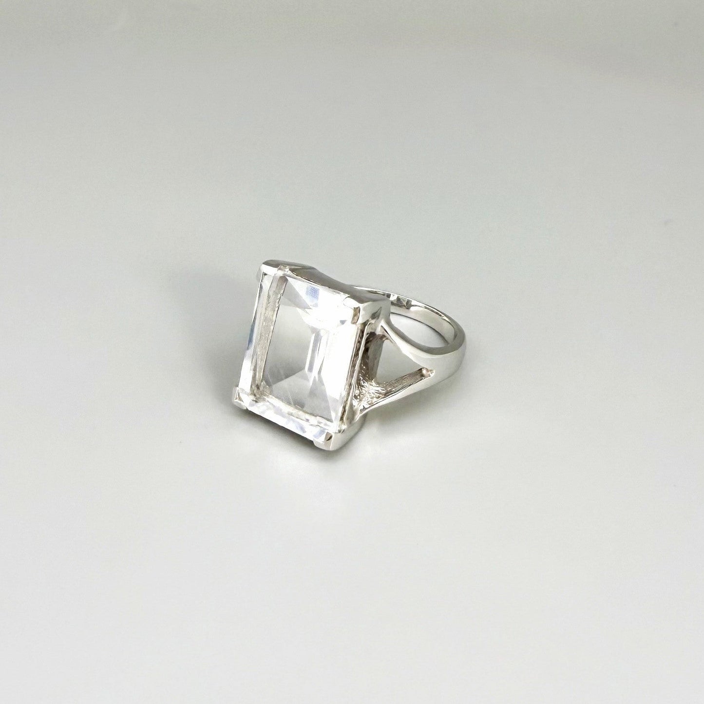 White quartz ring in white gold plated sterling silver, featuring a faceted clear gemstone with brilliant reflections, elegant and timeless design.