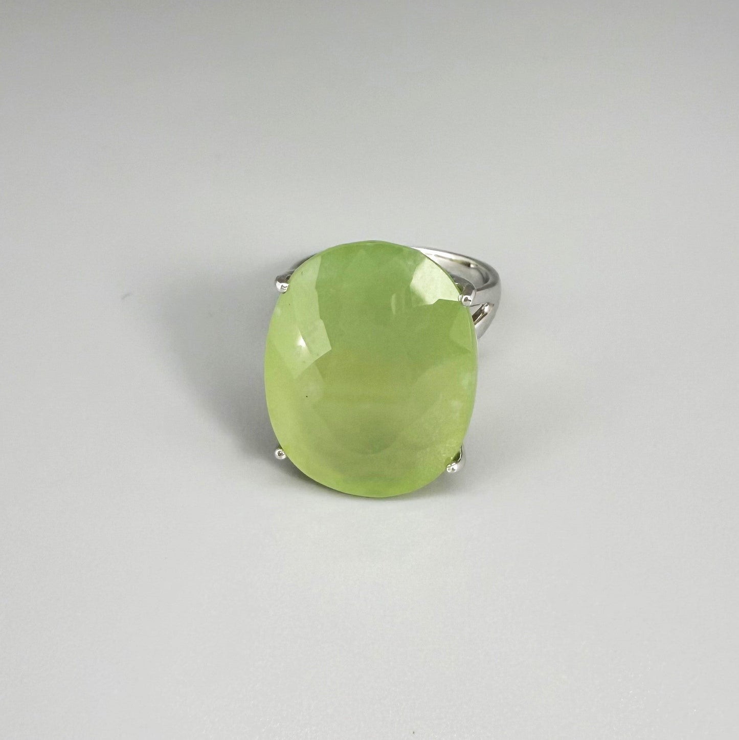 Chrysoprase ring in white gold plated sterling silver featuring an oval cabochon gemstone with light apple-green hue and smooth, natural translucence.