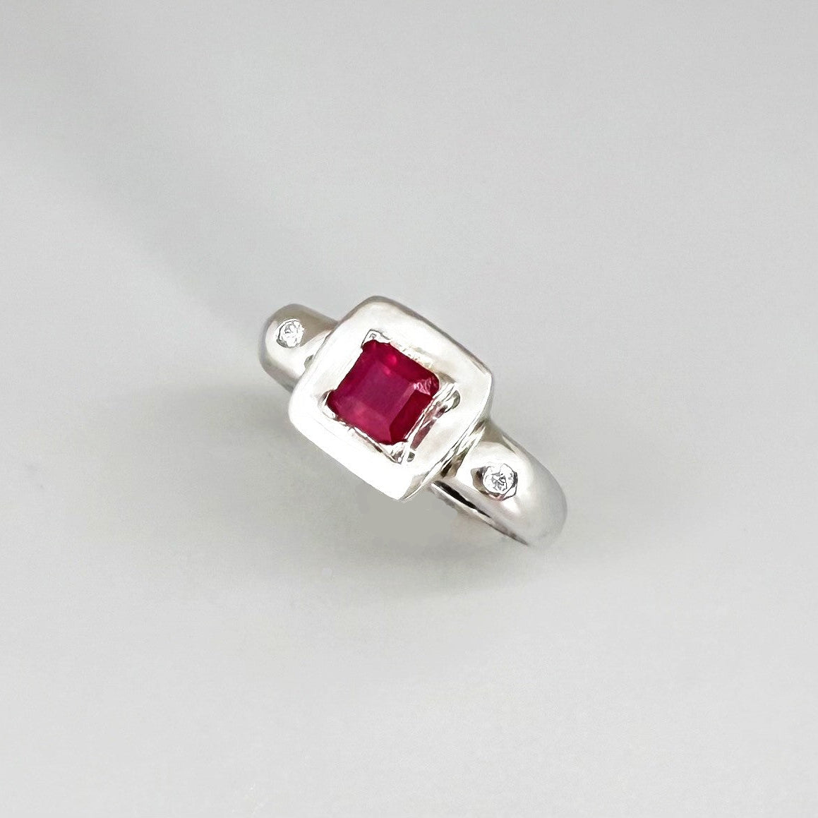 Ruby and CZ ring in white gold plated sterling silver, featuring a vivid red natural ruby framed by clear cubic zirconia, elegant and classic design.