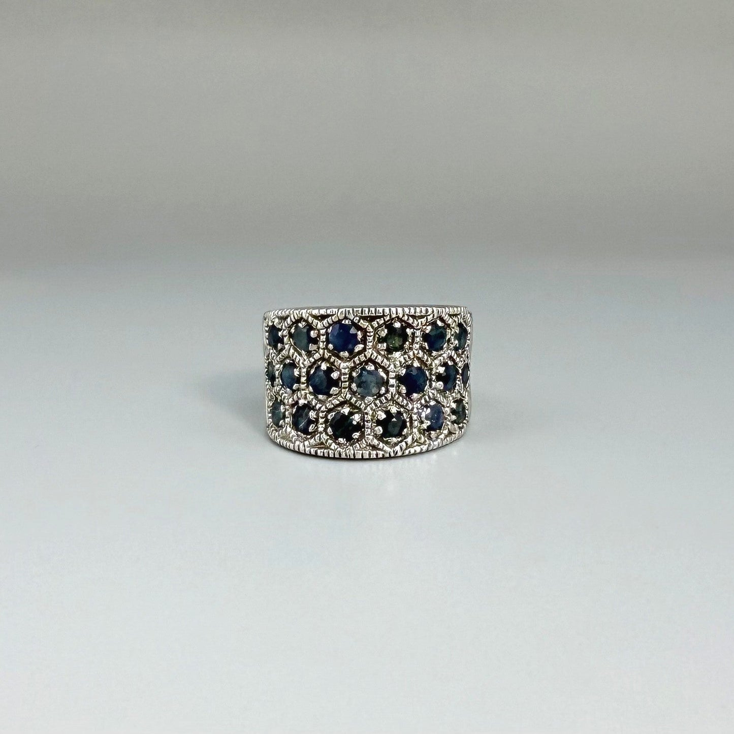 Wide band ring with light blue sapphires set in white gold plated sterling silver, reflecting soft blue brilliance with timeless elegance.