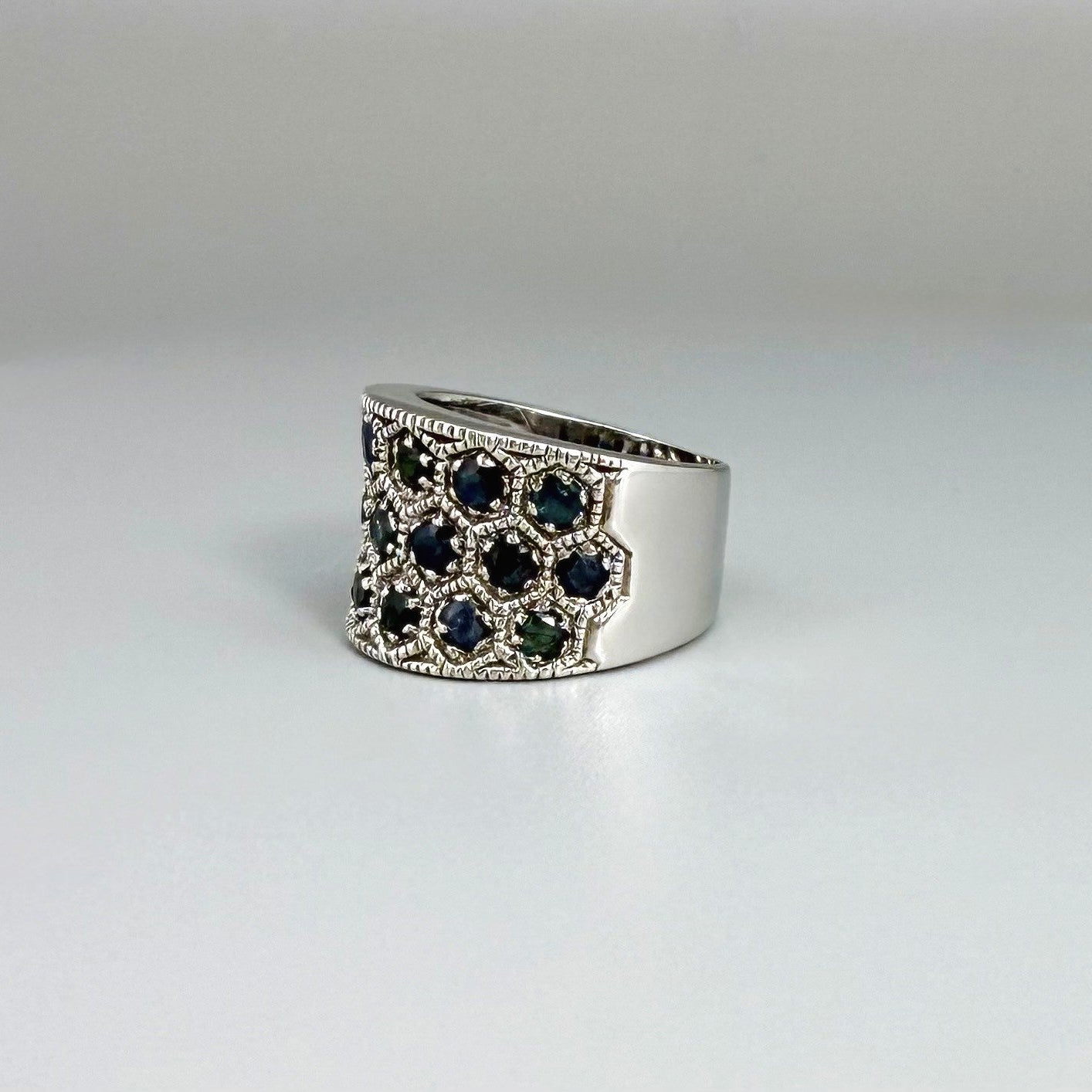 Wide band ring with light blue sapphires set in white gold plated sterling silver, reflecting soft blue brilliance with timeless elegance.