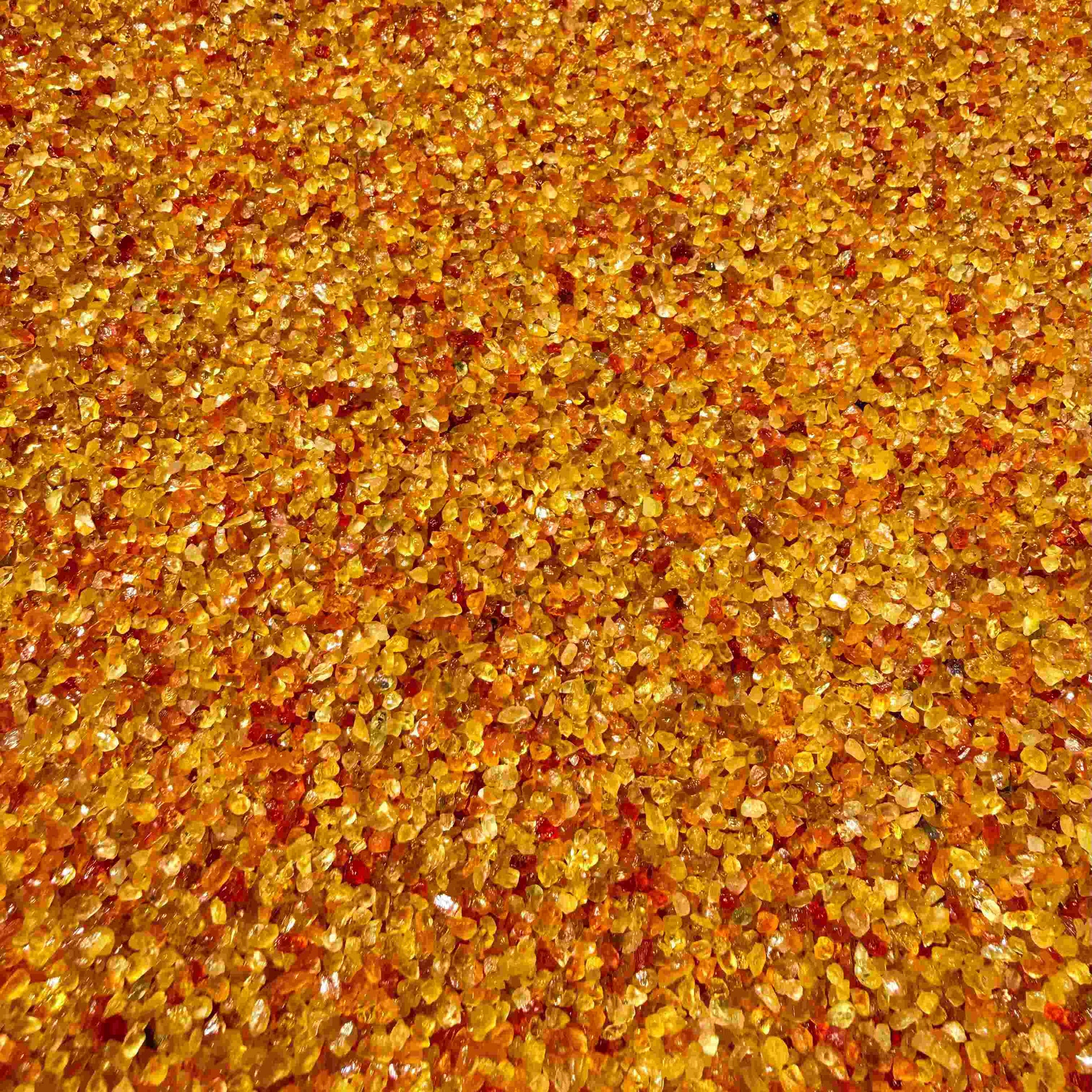 Natural sapphire rough with warm yellow-orange hues and subtle color variation, uncut corundum photographed on neutral background.