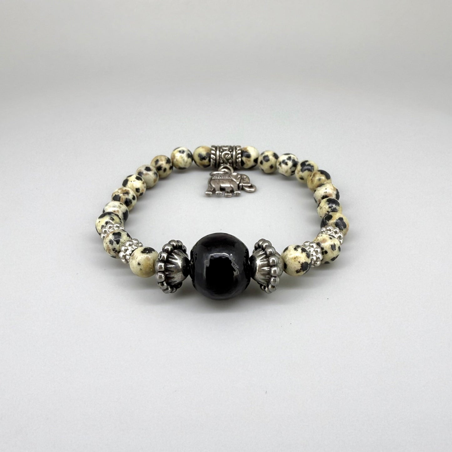 Dalmatian jasper beaded bracelet, 17cm, cream with black speckled gemstone beads and one large black accent bead on elastic stretch band.