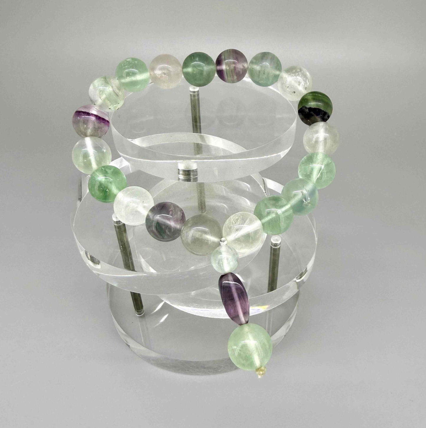 Fluorite mala bracelet with green and purple translucent gemstone beads and decorative charm detail.