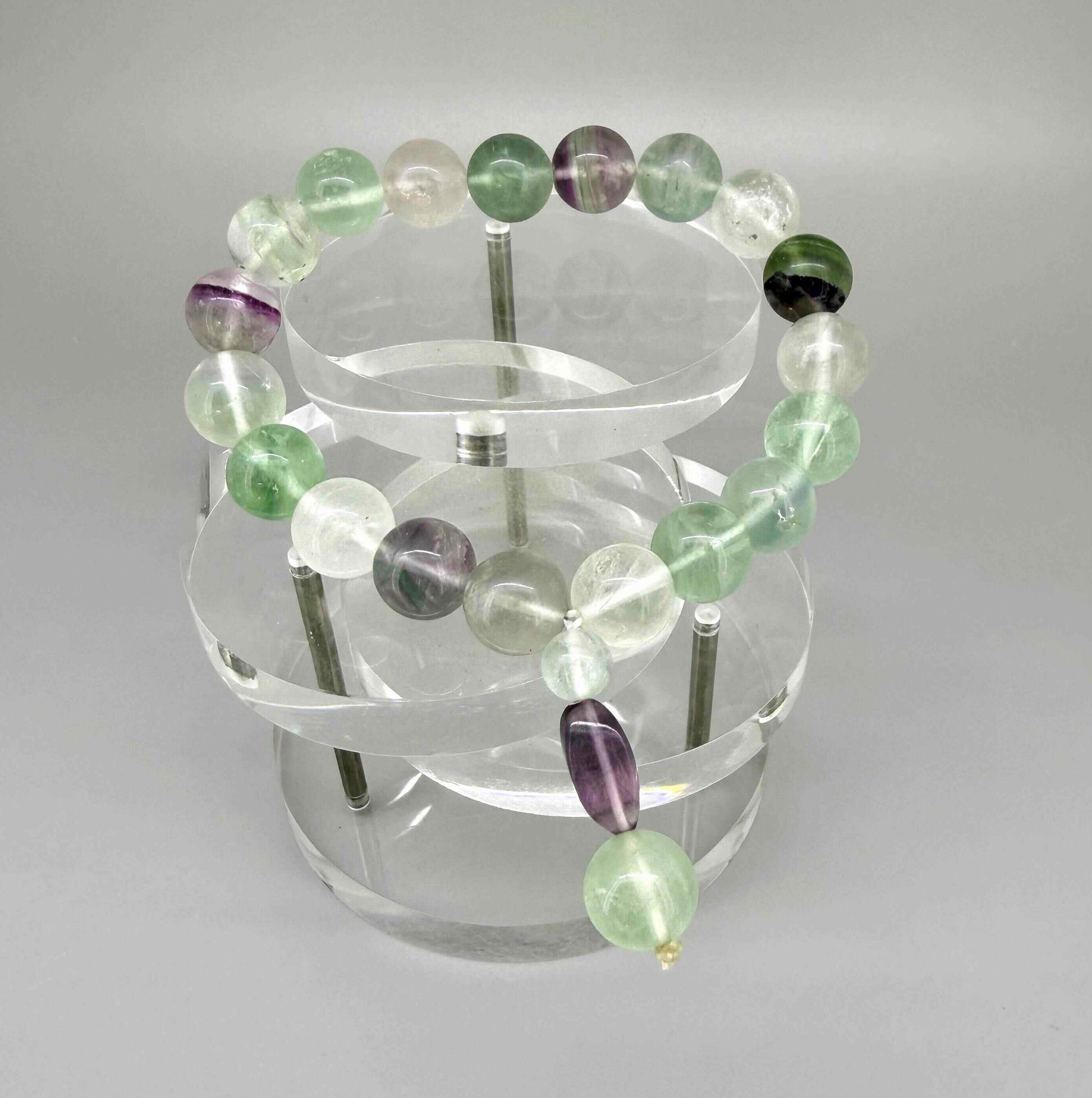 Fluorite mala bracelet with green and purple translucent gemstone beads and decorative charm detail.