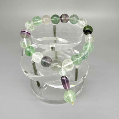 Fluorite mala bracelet with green and purple translucent gemstone beads and decorative charm detail.