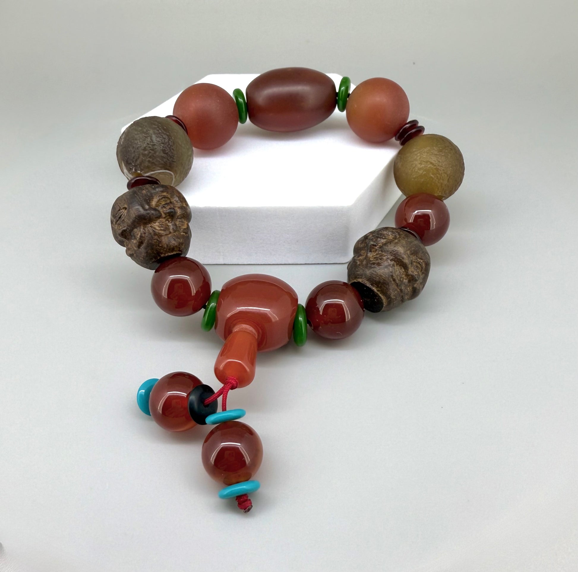 Carnelian and agate beaded bracelet, 20cm, orange-red and brown gemstone beads with two carved wooden head accents on elastic stretch band.