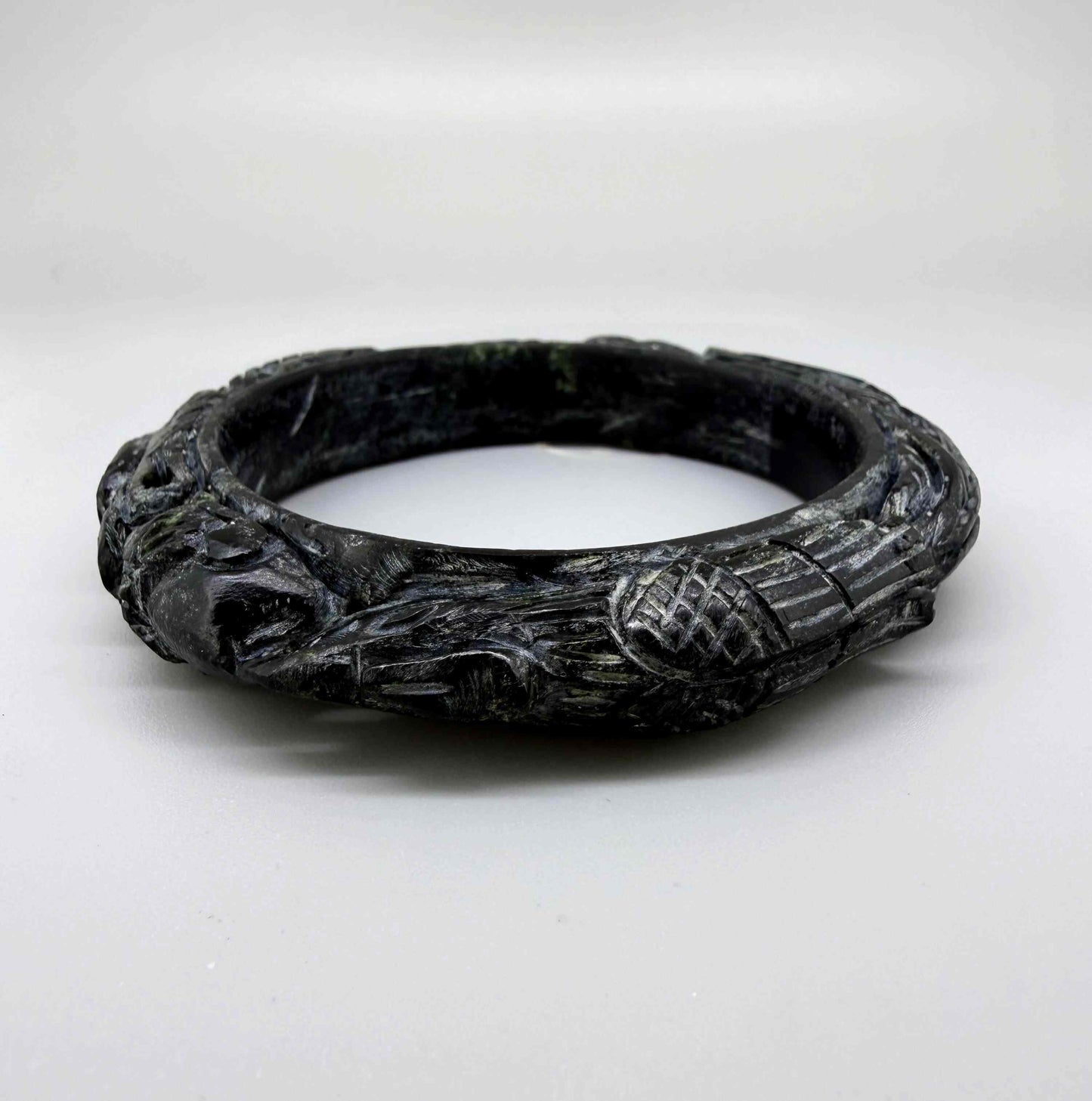 Carved dark jade-style bangle with sculptural relief details and polished surface, 19 cm inner circumference