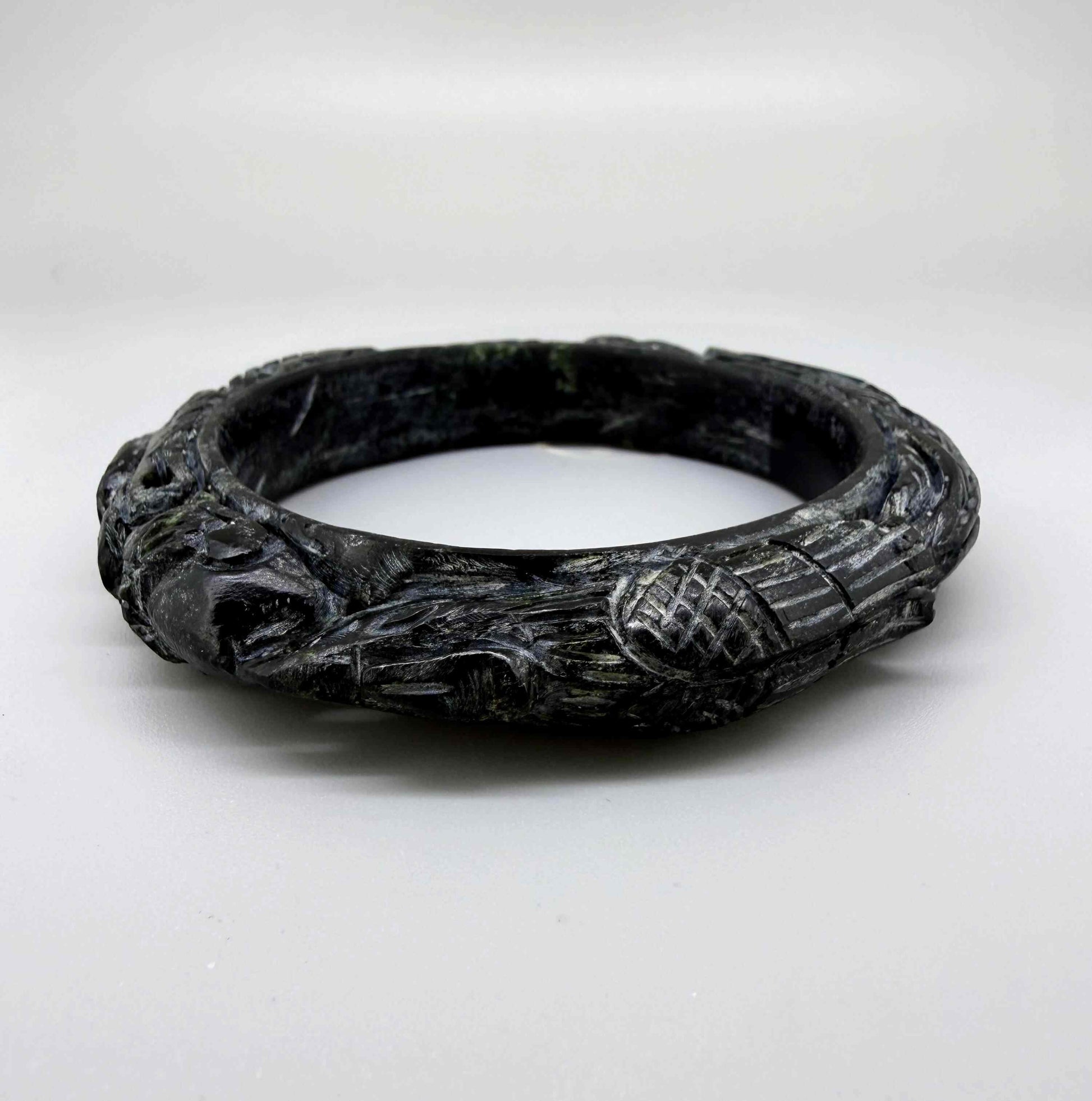 Carved dark jade-style bangle with sculptural relief details and polished surface, 19 cm inner circumference