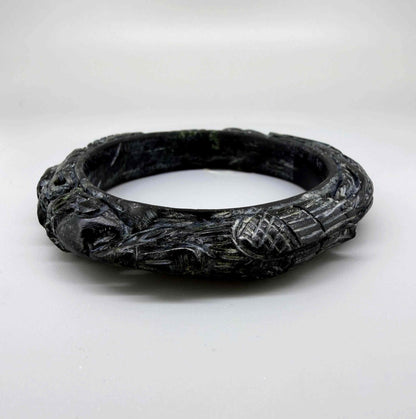 Carved dark jade-style bangle with sculptural relief details and polished surface, 19 cm inner circumference