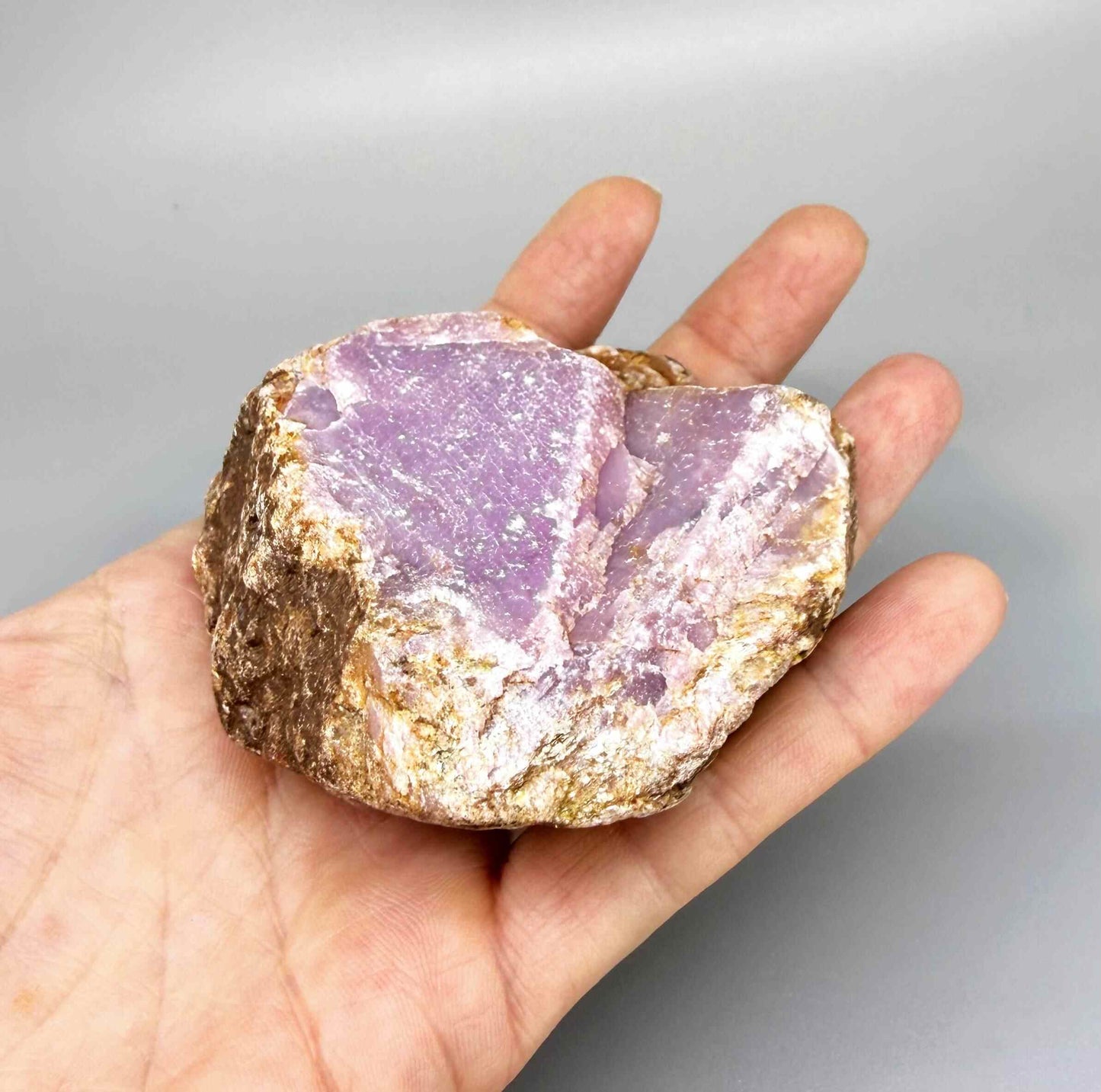 Natural ruby rough stone with purple-pink tones in host rock, uncut corundum specimen