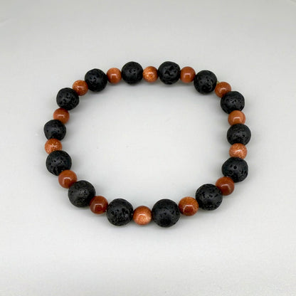 Lava and goldstone beaded bracelet, 18cm, alternating matte black lava beads and smaller shimmering golden-brown man-made goldstone beads on elastic stretch band.