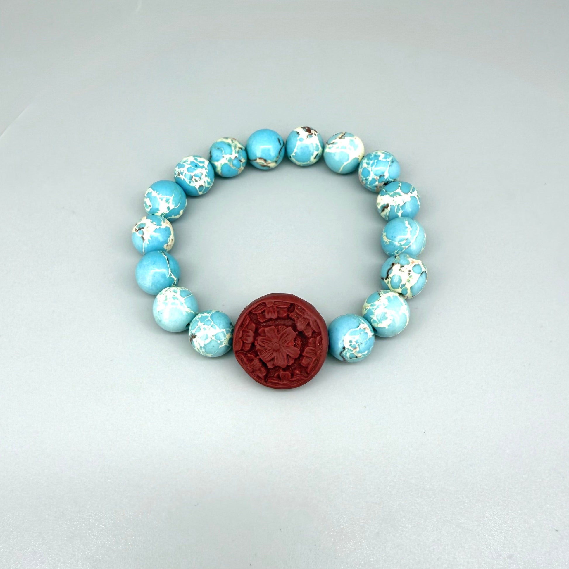 Varescite beaded bracelet, 18cm, turquoise-green gemstone beads with carved red cinnabar-style accent bead on elastic stretch band.