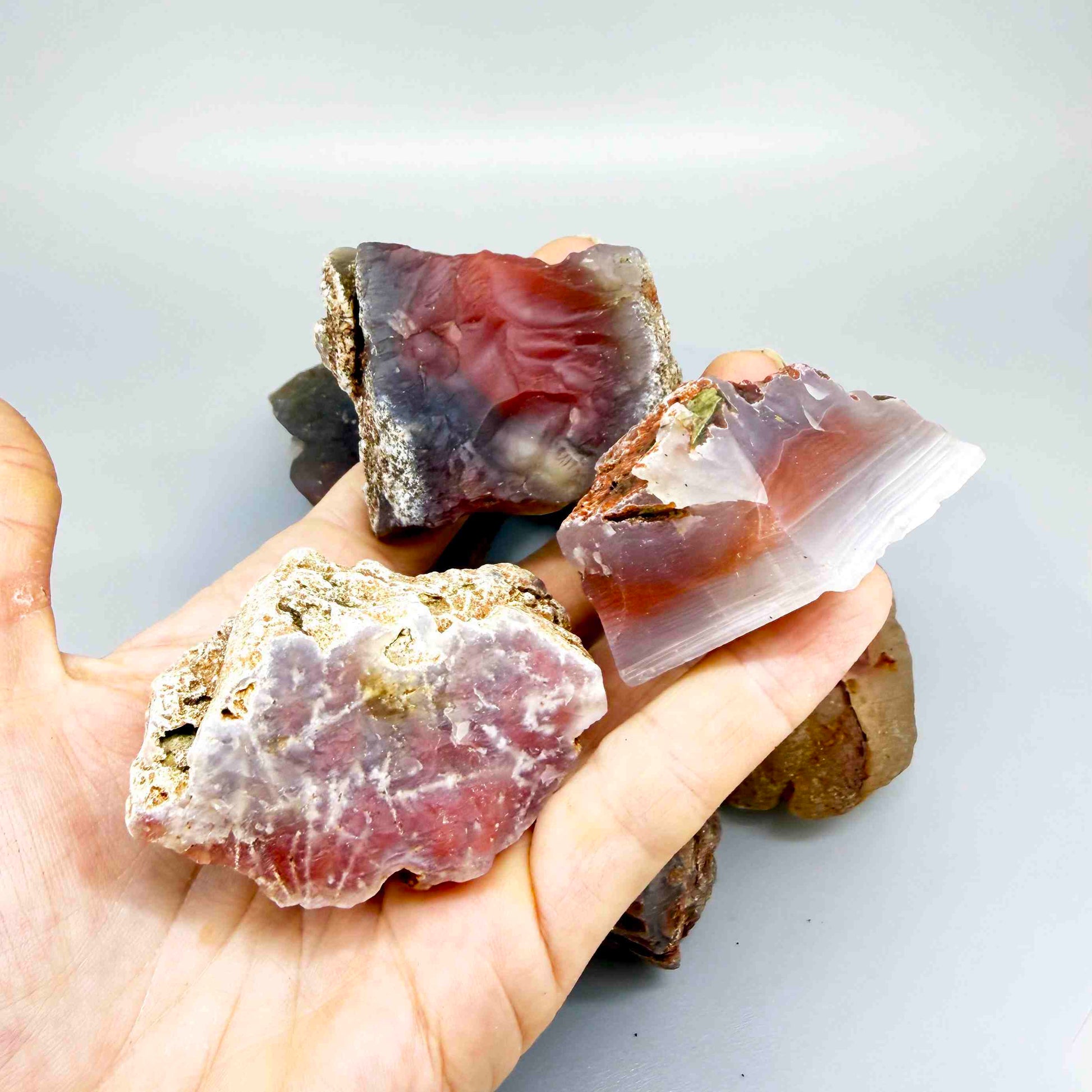Mixed chalcedony rough stones with pink, orange-red and grey banded patterns, natural quartz lot.