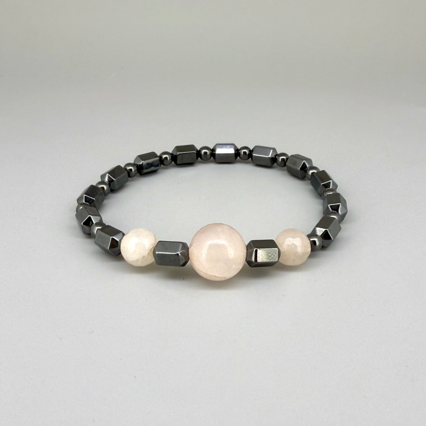 Hematite and rose quartz beaded bracelet, 18cm, geometric metallic grey beads with three pink rose quartz accents on elastic stretch band.