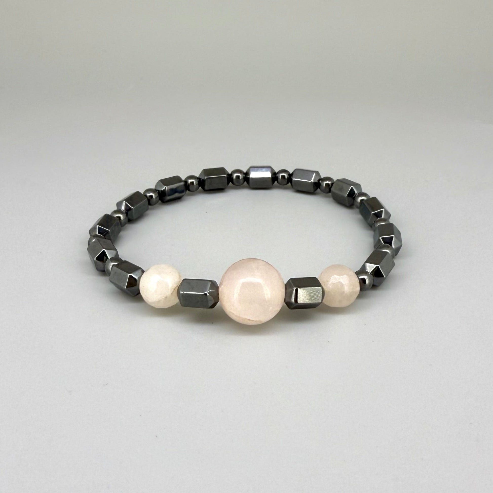 Hematite and rose quartz beaded bracelet, 18cm, geometric metallic grey beads with three pink rose quartz accents on elastic stretch band.