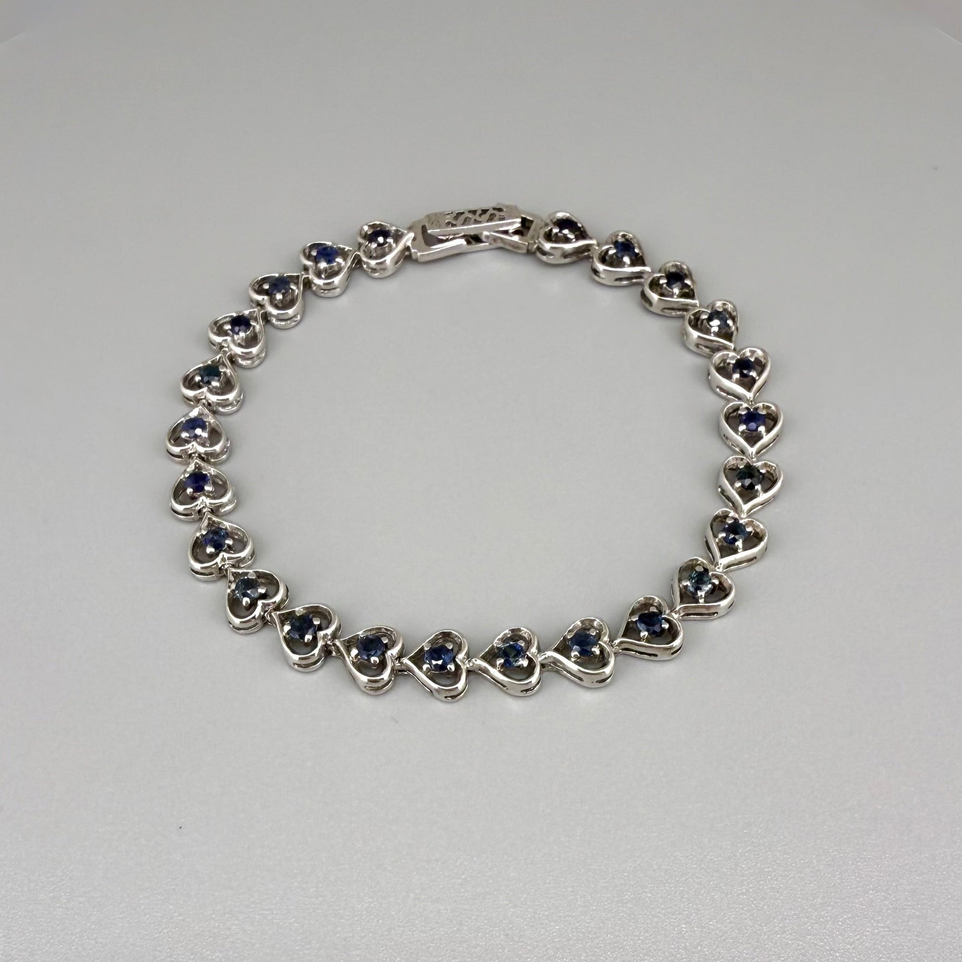 Sapphire bracelet in sterling silver with white gold plating, elegant design on neutral background