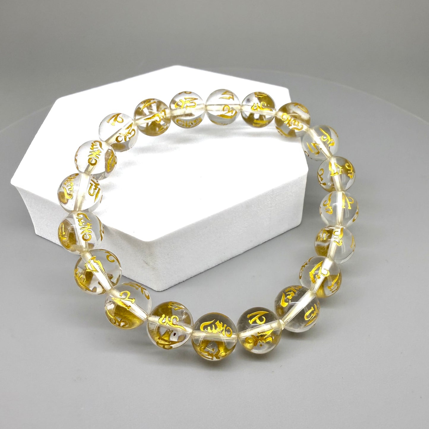 Clear quartz beaded bracelet, 19cm, transparent gemstone beads engraved with golden Sanskrit mantra Om Mani Padme Hum on elastic stretch band.