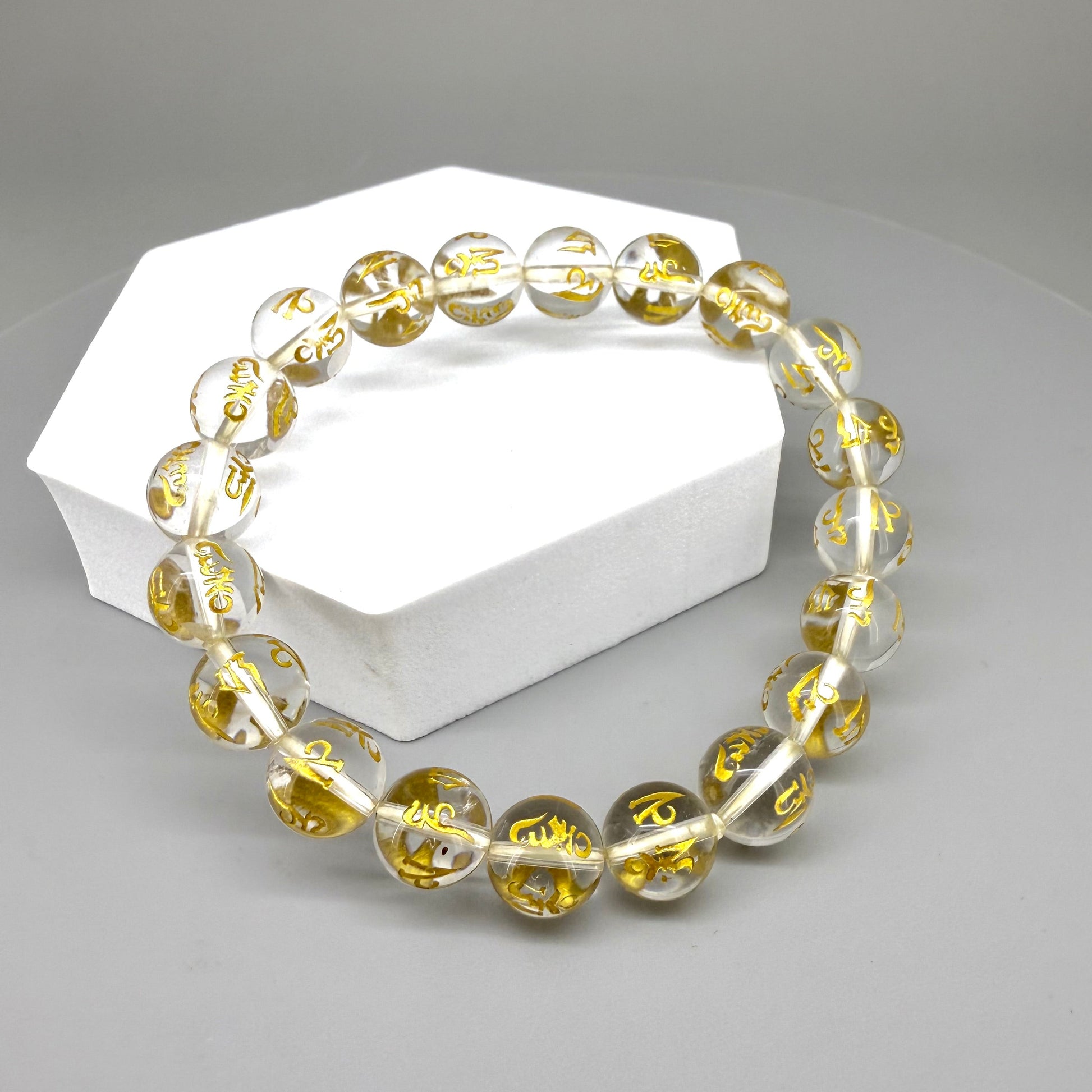 Clear quartz beaded bracelet, 19cm, transparent gemstone beads engraved with golden Sanskrit mantra Om Mani Padme Hum on elastic stretch band.