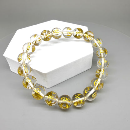 Clear quartz beaded bracelet, 19cm, transparent gemstone beads engraved with golden Sanskrit mantra Om Mani Padme Hum on elastic stretch band.