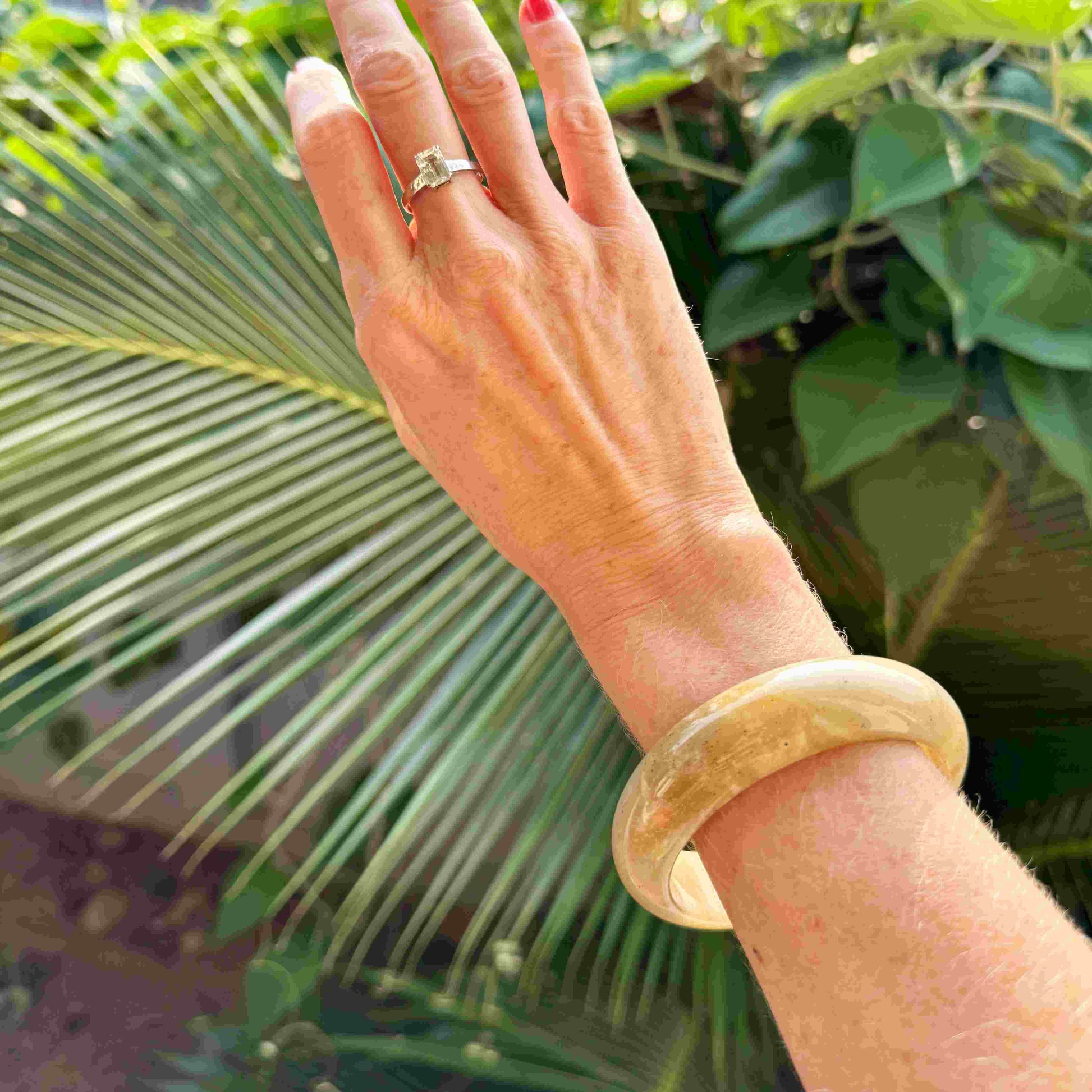 Polished jade bangle in soft earth tones with smooth surface and natural variations