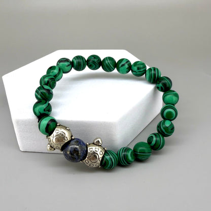 Malachite beaded bracelet, 18cm, green gemstone beads with central blue bead framed by two metal turtle accents on elastic stretch band.