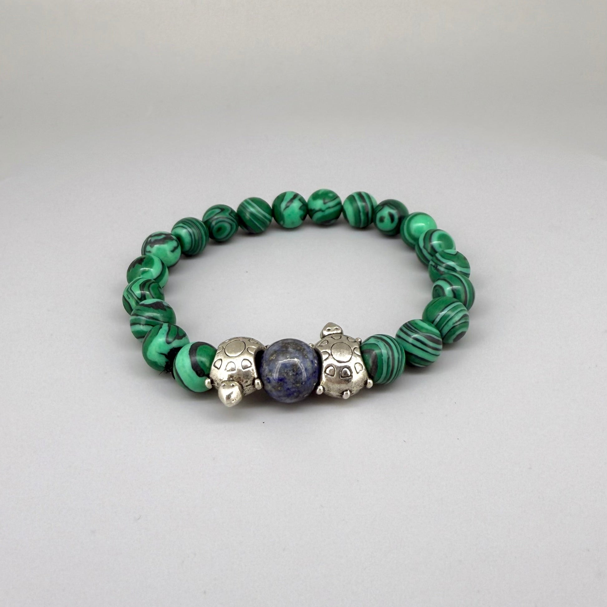 Malachite beaded bracelet, 18cm, green gemstone beads with central blue bead framed by two metal turtle accents on elastic stretch band.