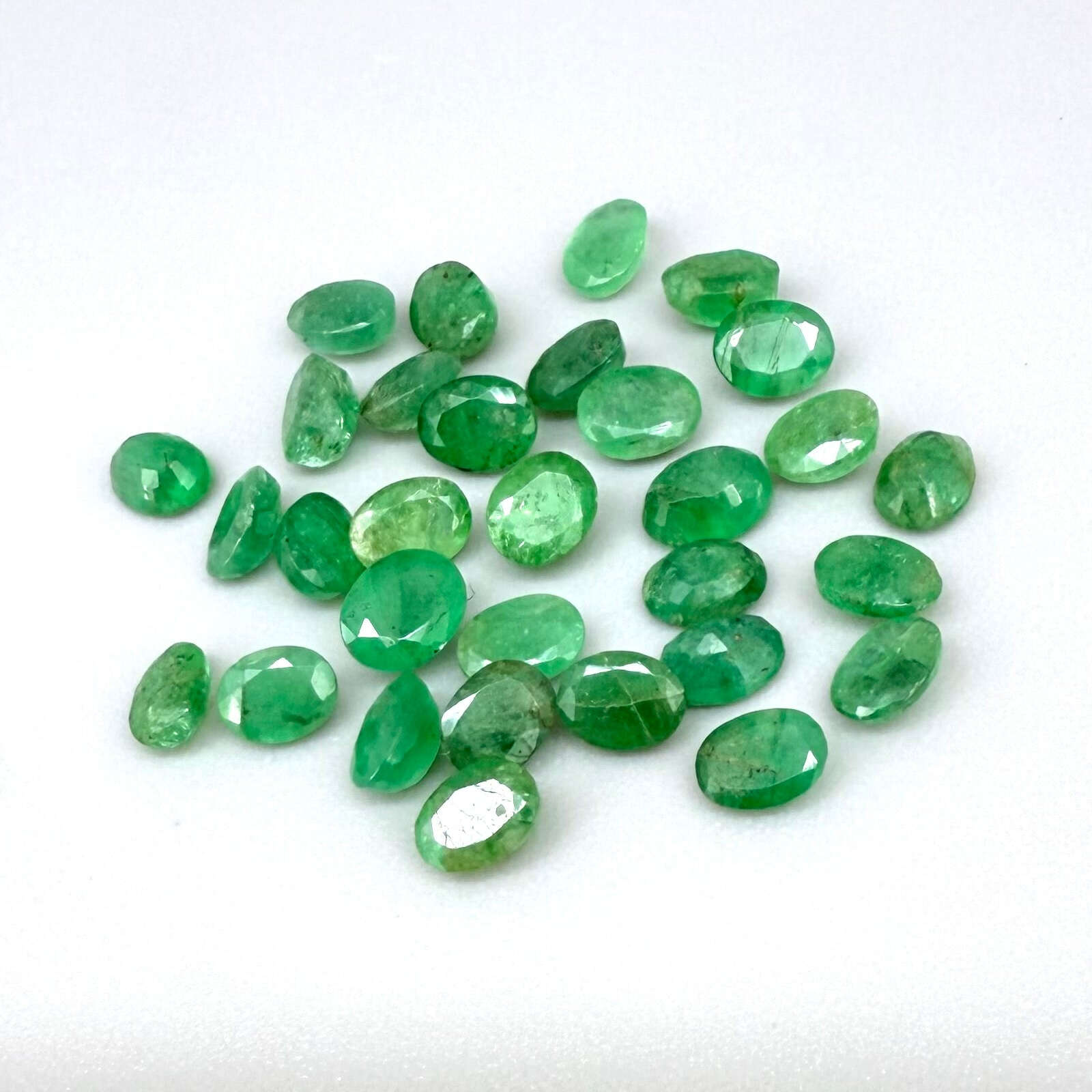 5.5 ct natural untreated Zambian emerald lot, faceted oval stones with vivid bluish-green color.