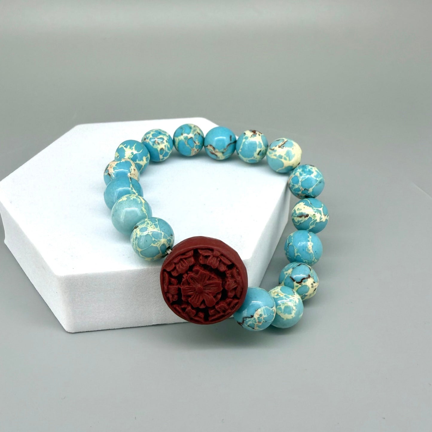 Varescite beaded bracelet, 18cm, turquoise-green gemstone beads with carved red cinnabar-style accent bead on elastic stretch band.