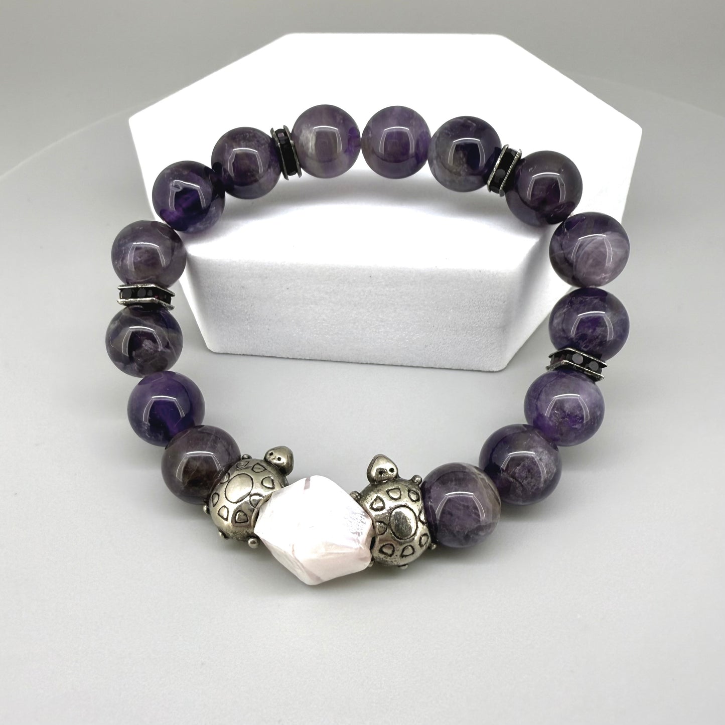 Amethyst beaded bracelet, 18cm, violet gemstone beads with pink-white accent stone and two metal turtle beads on elastic stretch band.