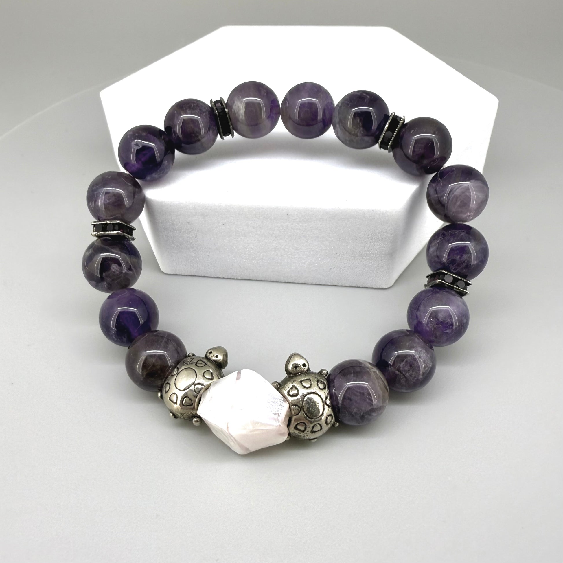 Amethyst beaded bracelet, 18cm, violet gemstone beads with pink-white accent stone and two metal turtle beads on elastic stretch band.