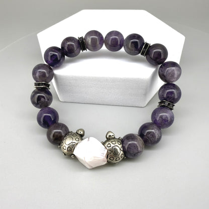 Amethyst beaded bracelet, 18cm, violet gemstone beads with pink-white accent stone and two metal turtle beads on elastic stretch band.
