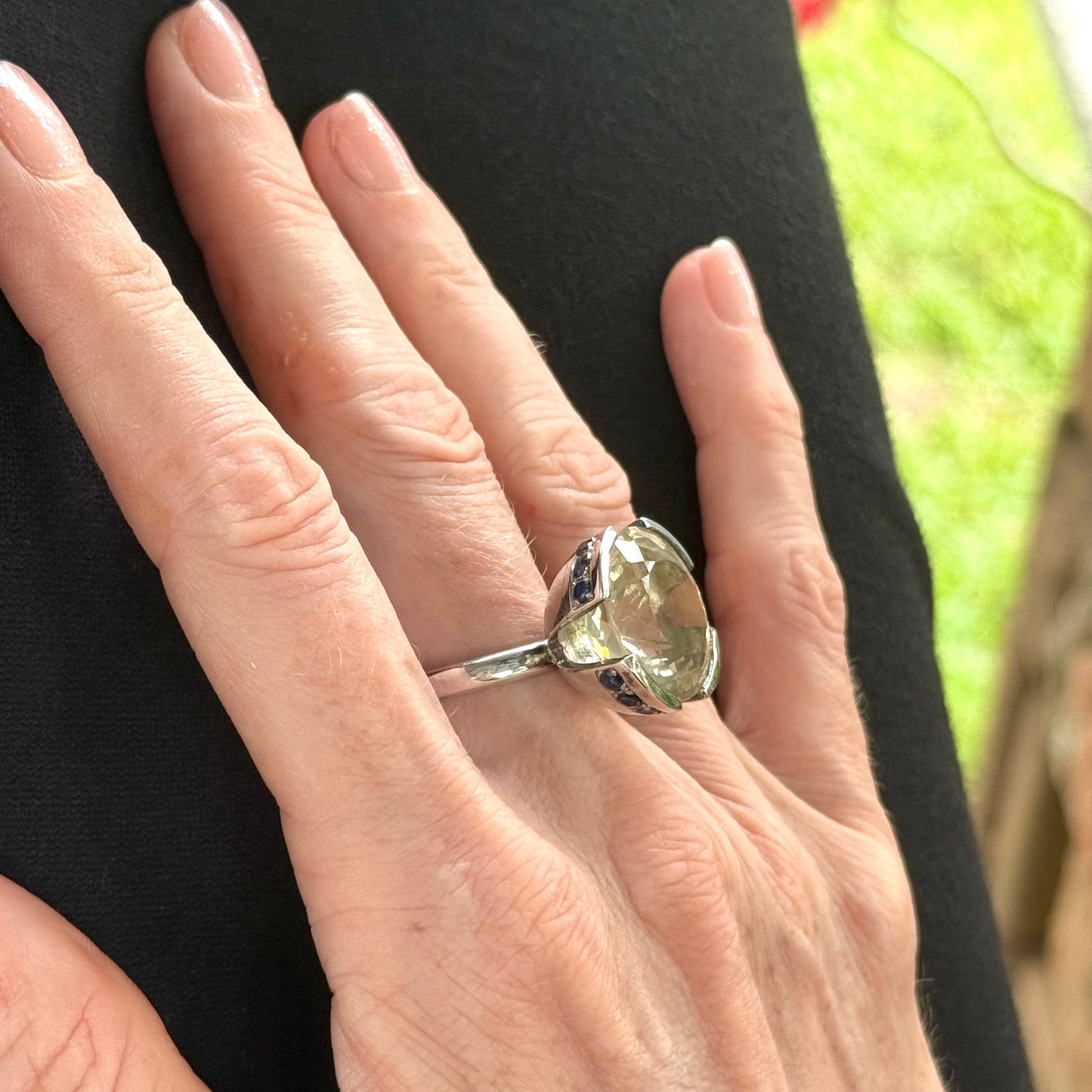 Lemon quartz and sapphire ring in white gold plated sterling silver, featuring a faceted yellow-green gemstone framed by deep blue sapphires, elegant and vibrant design.