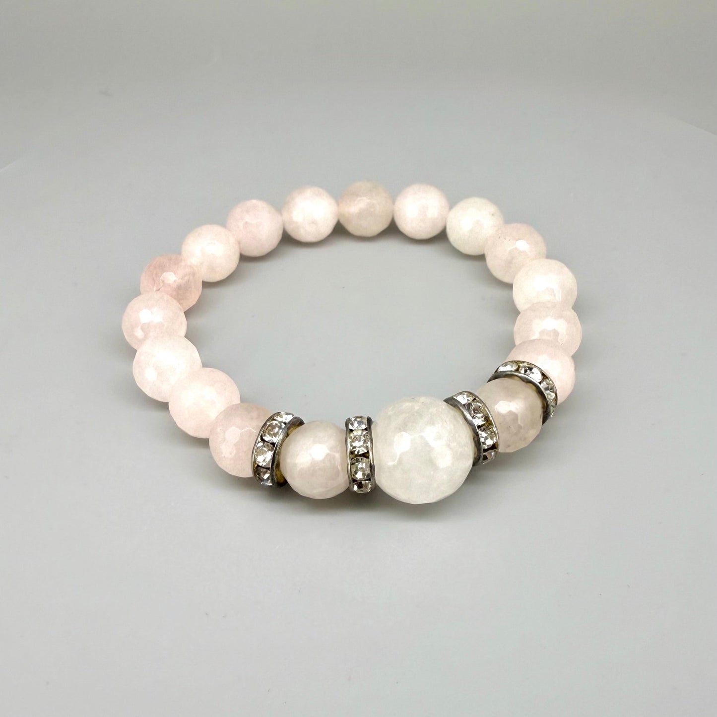 Rose quartz beaded bracelet, 18cm, light pink gemstone beads with larger central bead and decorative metal accents on elastic stretch band.
