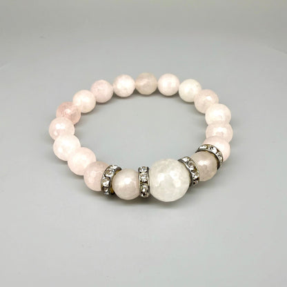 Rose quartz beaded bracelet, 18cm, light pink gemstone beads with larger central bead and decorative metal accents on elastic stretch band.