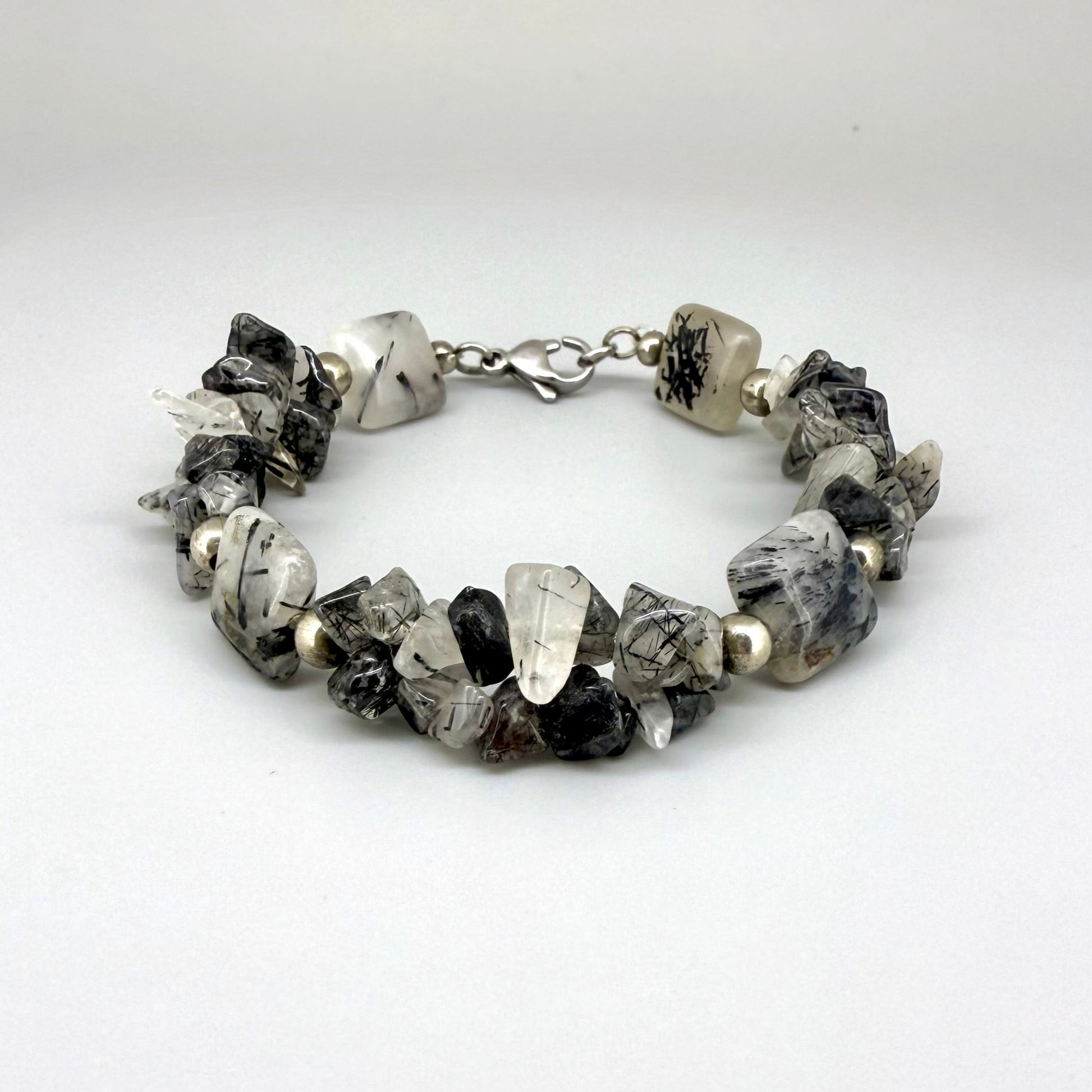 Rutilated quartz bracelet, 19cm, irregular nugget beads in grey, black, and white tones with metal spacers and clasp.